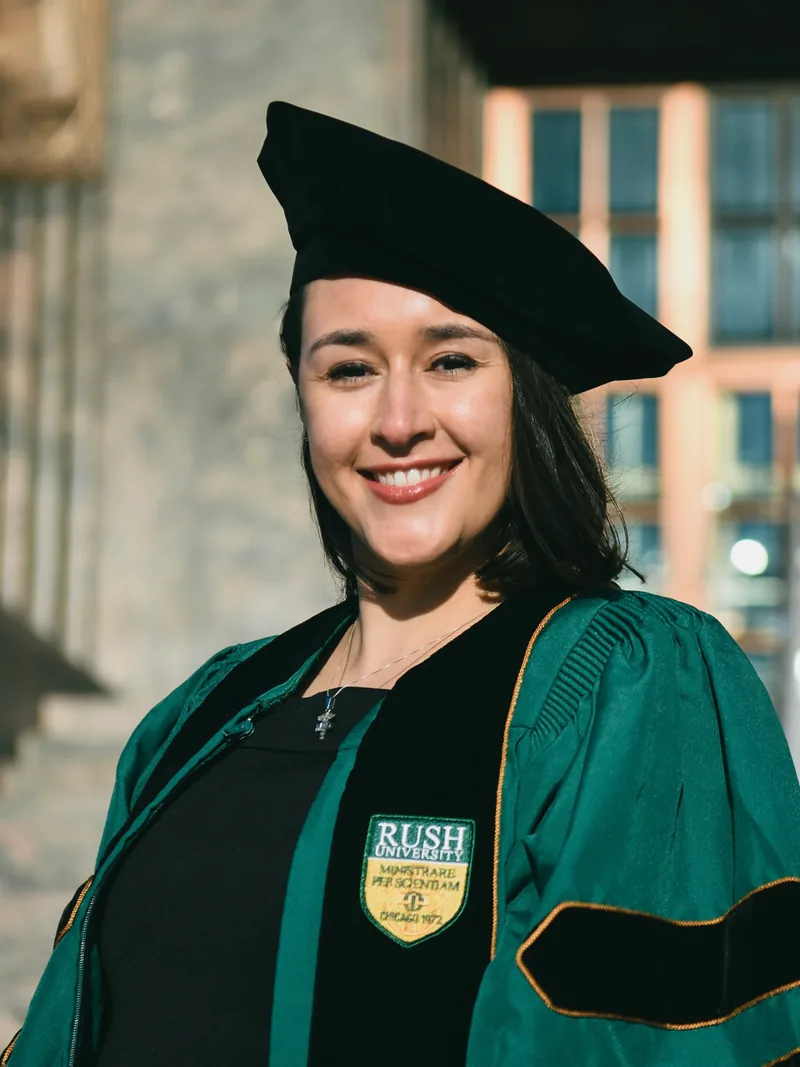 Stephanie Moss in green and black Rush University doctoral regalia and cap on graduation day.
